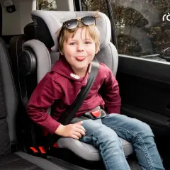 Chłopiec w foteliku samochodowym Britax Römer, z językiem na wierzchu, w okularach przeciwsłonecznych na głowie. Jaki fotelik samochodowy wybrać?