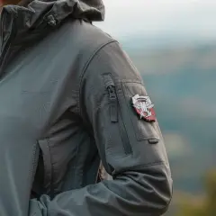 Szara kurtka z naszywką, idealna do zastosowania impregnatu do kurtek przeciwdeszczowych. Wygoda i ochrona w każdych warunkach.