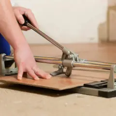 Mano che usa un tagliapiastrelle per tagliare una piastrella. Impara come forare le piastrelle con questo strumento.