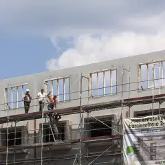 Chantiers de construction : des ouvriers sur des échafaudages travaillent sur un immeuble en cours de construction, projet de crédit immobilier avec travaux.