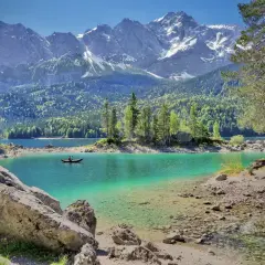 Ein Kajakfahrer genießt die Ruhe auf einem türkisfarbenen See vor majestätischen Bergen. Perfekte unternehmungen bayern für Naturliebhaber.