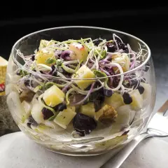 Deliciosa ensalada de endivias con trozos de queso Gruyère, arándanos y brotes frescos, servida en copa de cristal.