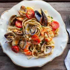 Un piatto invitante di scialatielli ai frutti di mare, con cozze, vongole, gamberi e pomodorini freschi, guarnito con prezzemolo.