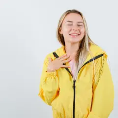 Uśmiechnięta blondynka w żółtej kurtce softshell. Dowiedz się, jak prać softshell, by zachować jego właściwości.
