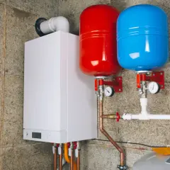 Chaudière blanche avec deux réservoirs de couleur rouge et bleue, un vase d'expansion essentiel pour le bon fonctionnement du système de chauffage.