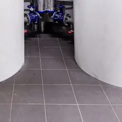 Szare płytki w kotłowni, między białymi zbiornikami. W tle widać instalację hydrauliczną z niebieskimi zaworami.