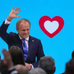 Donald Tusk macha do tłumu na tle niebieskiego ekranu z sercem. Czy to koalicja?