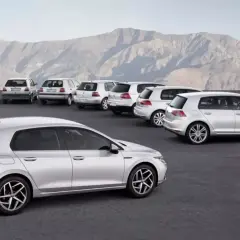 Ewolucja modelu golf 9. Rząd srebrnych samochodów, od klasycznych po nowoczesne, na tle gór.