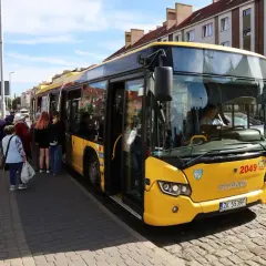 Żółty autobus PKS czeka na pasażerów w Koszalinie, gotowy do podróży do Dąbek.