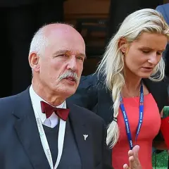 Janusz Korwin-Mikke z wąsem i w muszce, obok niego kobieta w czerwonej sukience. Może to jego dzieci?