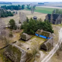 Skansen wsi łowickiej z drewnianymi chatami, kościołem i wieżą.