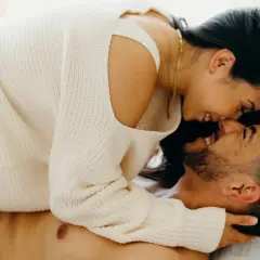 A couple embracing intimately, with the woman leaning over the man.