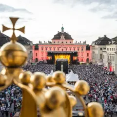 Goldener Blick auf ein riesiges Publikum bei **live musik ludwigsburg**. Die Barockfassade des Schlosses erstrahlt im Abendlicht.