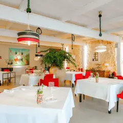Interni eleganti di ristoranti stellati Puglia, con tavoli apparecchiati, sedie rosse vivaci e un'opera d'arte colorata.