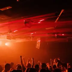 Folla in delirio in una delle tante discoteche techno, con luci laser rosse che illuminano la scena.