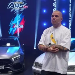 Mężczyzna w koszulce z bananem stoi między Mercedesem A45 a BMW M3.