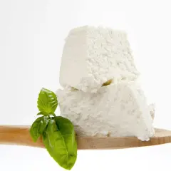 Ricotta fresca su cucchiaio di legno con basilico, un assaggio di come si fa la ricotta in caseificio.