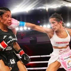 A boxer lands a powerful jab cross, her pink glove connecting with her opponent's face.