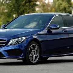 Granatowy Mercedes Klasy C, idealny do poznania jego **mercedes c klasa dane techniczne**. Elegancki sedan na tle zieleni.