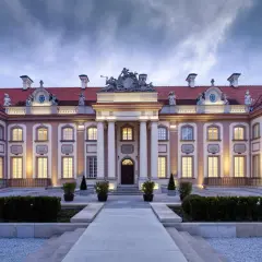 Elegancki pałac z czerwonym dachem i oświetlonymi oknami, wieczorem.