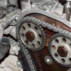 Primer plano de un motor con cadena de distribución, mostrando los engranajes y la cadena metálica.