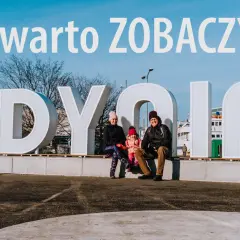 Rodzina pozuje przy napisie GDYNIA, odkrywając atrakcje turystyczne miasta.