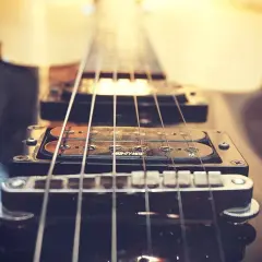 Zbliżenie na czarną gitarę elektryczną, jej struny i przetworniki. Czy to brzmienie mainstream co to?