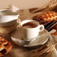 Idealne włoskie śniadanie: filiżanka espresso, mlecznik, dwa ciastka z nadzieniem i kłosy zboża.