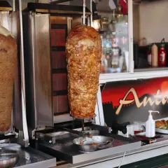 Dwa pionowe rożna z mięsem do kebaba na tle szyldu "Antalya".