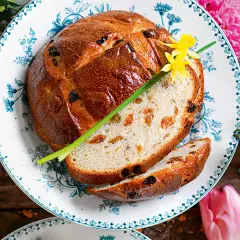 Pan di ramerino dorato, con uvetta e scorze candite, guarnito con un fiore giallo e un rametto verde.