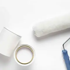 Rullo e barattolo di pittura bianca pronti per dipingere su pittura al quarzo.