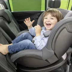 Uśmiechnięty chłopiec w foteliku samochodowym Britax Römer.