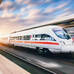 Biały pociąg z czerwonym pasem pędzi po torach, tworząc wrażenie ruchu. Trakcja kolejowa napięcie jest kluczowe dla jego podróży.