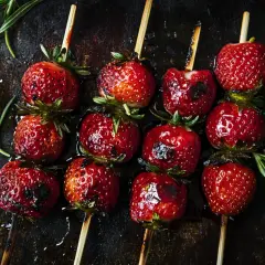 Zuckersüße Erdbeeren auf Spießen, leicht gegrillt und glänzend, mit Rosmarin garniert. Ein Genuss für alle Sinne!