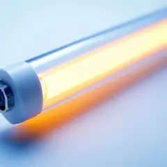 Świecąca na żółto świetlówka z widocznymi oznaczeniami na metalowym mocowaniu.