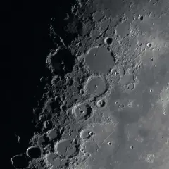 Zbliżenie na powierzchnię Księżyca z licznymi kraterami i cieniami.