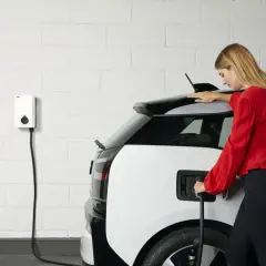 Femme branchant sa voiture électrique sur une borne. Une solution pratique pour le crédit d'impôt borne électrique.