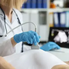 Lekarz wykonuje badanie USG piersi. Na ekranie widoczny obraz, sugerujący ocenę BIRADS 5.