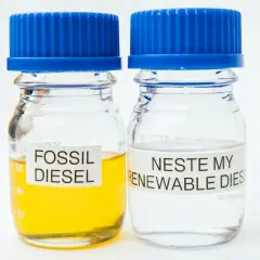 Två provrör med blå korkar. Ett innehåller gulaktig fossil diesel, det andra klar Neste my renewable diesel.