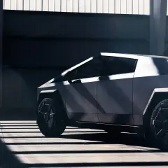 Futurystyczny Cybertruck Tesla w surowym wnętrzu, oświetlony promieniami słońca.