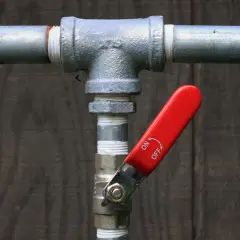 Metalowe rury z zaworem i czerwoną rączką. Zastanawiasz się, jak przeczyscic rury? Ten zawór może być kluczem.