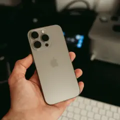 Dłoń trzyma nowy iPhone 16 ultramaryna. Z tyłu widoczny moduł aparatów i logo Apple.