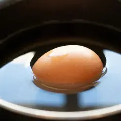 Un œuf frais flotte dans l'eau d'une casserole, prêt à être cuit.