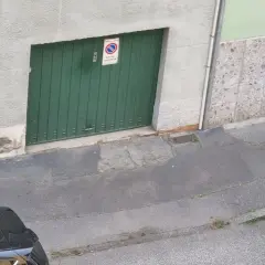 Porta garage verde con cartello "passo carrabile". Spazio di manovra libero.