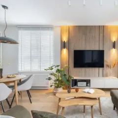 Przytulny salon inspiracje: drewniana ściana z TV, jadalnia z okrągłym stołem, wygodne fotele i stolik kawowy.