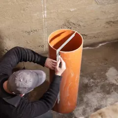 Mann markiert Rohr für Pumpensumpf im Keller, um Grundwasser abzuleiten.