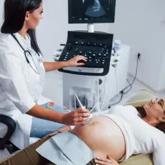 Lekarka wykonuje badanie USG ciężarnej. Na ekranie widoczny obraz płodu, a obok aparat USG. BPD USG co oznacza? To pomiar dwubocznej średnicy główki płodu.