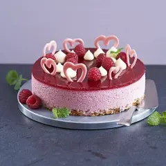En vacker hallonmousse tårta med färska hallon och rosa hjärtdekorationer, perfekt för ett speciellt tillfälle.