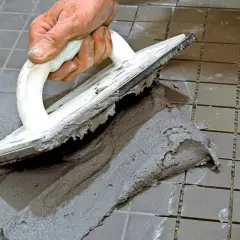 Hand spreading cement with a trowel to foga om kakel.
