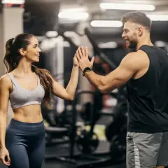 Coppia si dà il cinque in palestra, ispirata da schede palestra con immagini per un allenamento efficace.